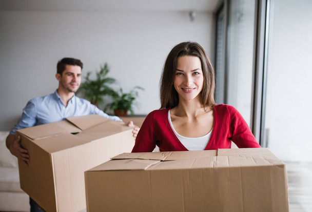 Young couple with cardboard boxes moving in a new home. - Foto, afbeelding