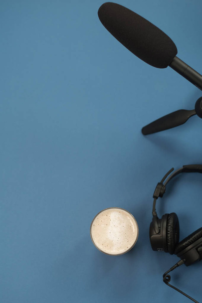 Flat lay composition with Headphones, microphone and coffee on a blue background. Podcast or webinar concept. - Foto, Bild