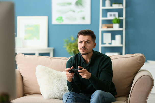 Молодой человек играет в видеоигры дома - Фото, изображение