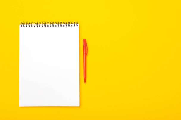Mesa de espaço de trabalho com notebook e caneta com copyspace isolado em fundo amarelo
 - Foto, Imagem