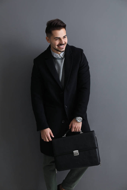 Стильний красивий чоловік з портфелем на сірому фоні
 - Фото, зображення