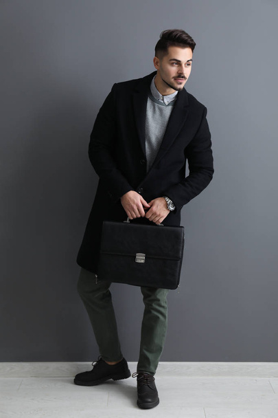 Elegante hombre guapo con maletín cerca de la pared gris
 - Foto, Imagen