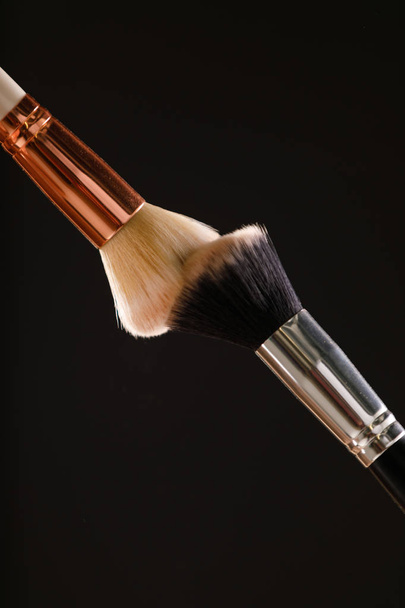 Make up cosmetic brushes with powder blush explosion on black background - Photo, Image