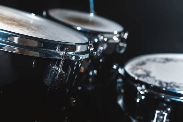 Closeup view of a drum set in a dark studio. Black drum barrels with chrome trim. The concept of live performances - Fotoğraf, Görsel