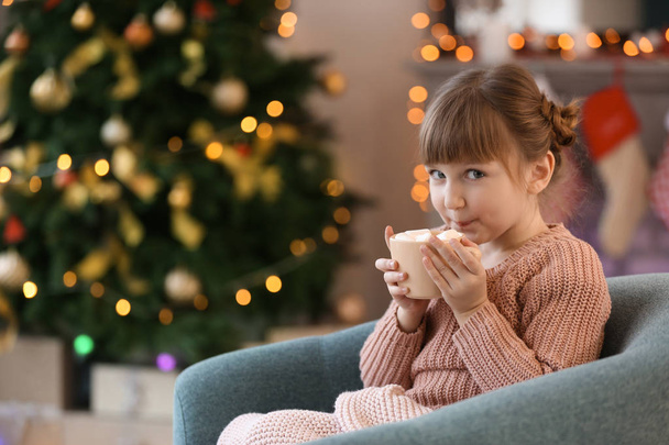 Linda niña bebiendo chocolate caliente en casa en la víspera de Navidad
 - Foto, Imagen