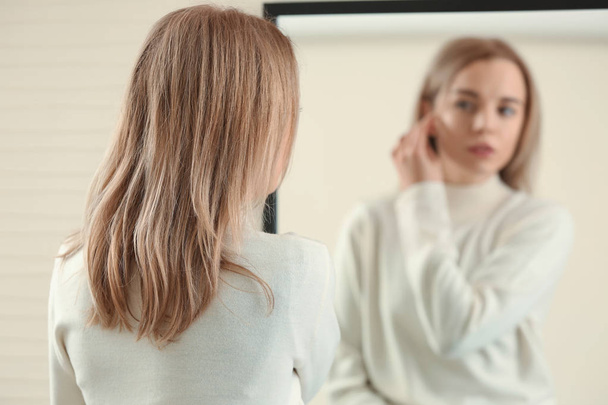 Красива молода жінка дивиться на своє відображення у дзеркалі
 - Фото, зображення