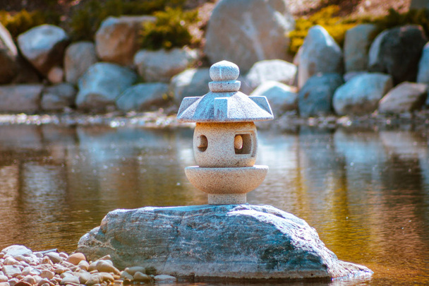 Japanese lantern statue stands alone on a peninsula in the japanese gardens - Zdjęcie, obraz