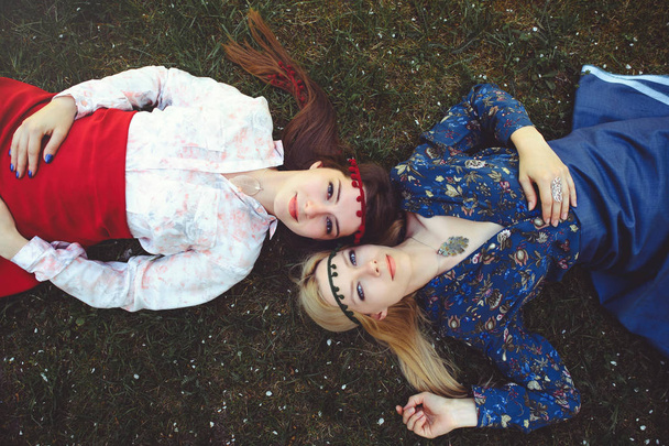 Portret młodego pięknych kobiet, leżąc na trawie. Widok z góry szczęśliwy. Dziewczyna jest ubrana stylowo, Biżuteria na głowie. -obraz - Zdjęcie, obraz