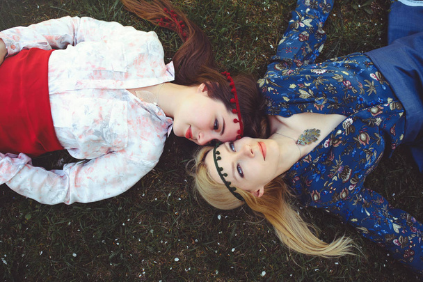 Portrét mladé krásné ženy ležící na trávě. pohled shora je šťastný. Dívka je oblečená stylově, šperky na hlavě. -obrázek - Fotografie, Obrázek