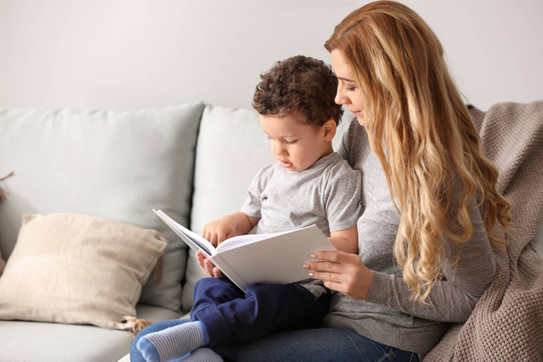 Young mother with cute little son reading book at home - Φωτογραφία, εικόνα