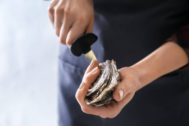 Woman opening raw oyster with knife, closeup - Foto, imagen