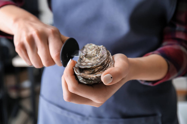 Woman opening raw oyster with knife, closeup - Photo, Image