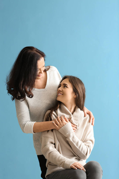 Portrait of young woman with her mother on color background - Photo, Image
