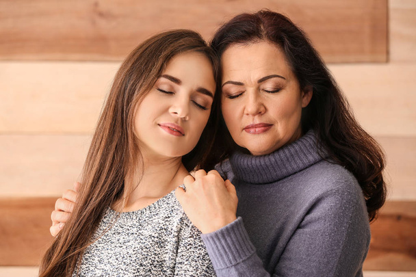 Portrait of young woman with her mother on wooden background - Foto, Imagem