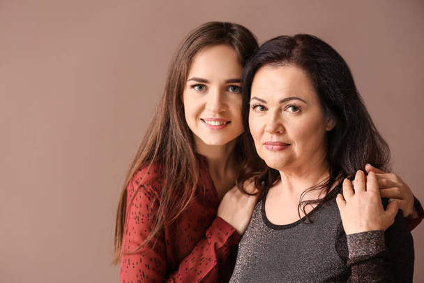 Portret van een jonge vrouw met haar moeder op kleur achtergrond - Foto, afbeelding
