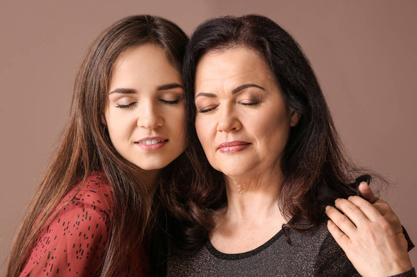 Portret van een jonge vrouw met haar moeder op kleur achtergrond - Foto, afbeelding