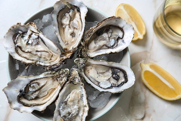 Plate with tasty cold oysters on light table - Photo, Image