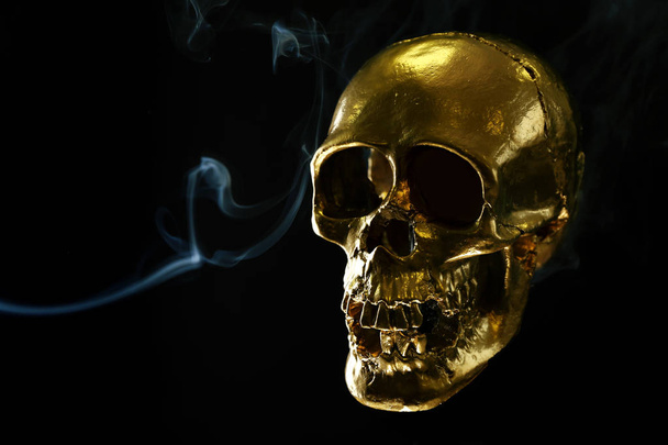 暗い背景に煙で黄金の人間の頭蓋骨 - 写真・画像