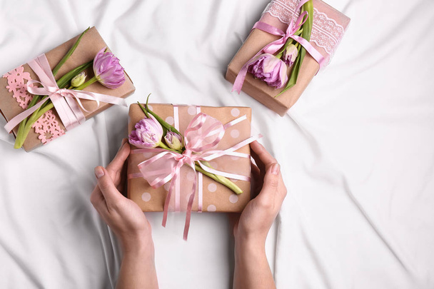 Γυναικεία χέρια με χειροποίητο δώρο κουτιά και λουλούδια επάνω ελαφρύς υπόβαθρο - Φωτογραφία, εικόνα
