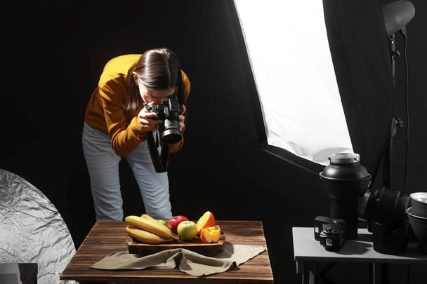 Young woman taking picture of tasty fruits in professional photo studio - Photo, Image