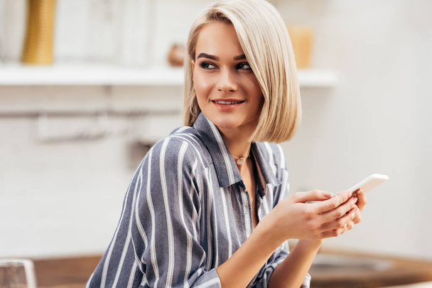 selective focus of attractive woman holding smartphone and smiling - Φωτογραφία, εικόνα