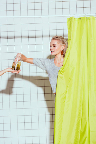 beautiful woman taking pickled cucumber from glass jar in shower - Photo, Image