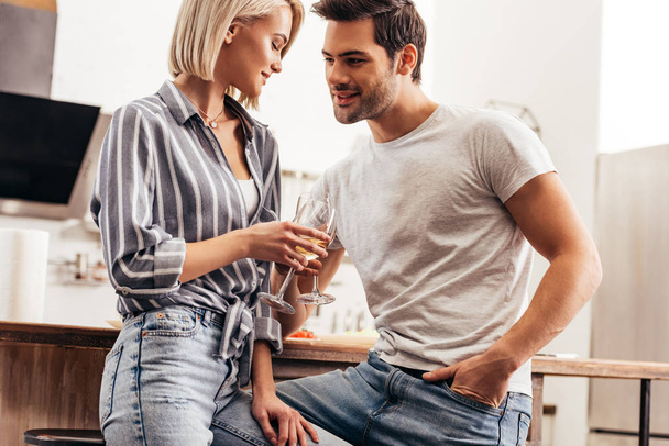handsome boyfriend putting hand in pocket and girlfriend holding wine glasses  - Foto, imagen