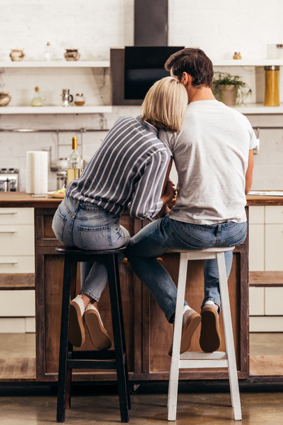 boyfriend and attractive girlfriend sitting on chairs in kitchen - Foto, immagini