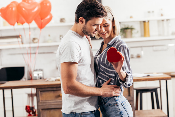 selective focus of handsome boyfriend hugging and giving gift to attractive girlfriend on Valentines day - Fotoğraf, Görsel