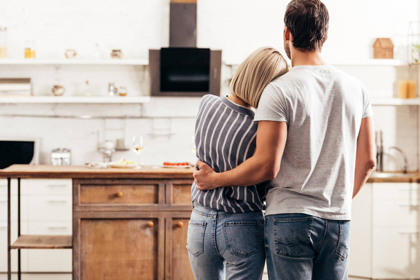 selective focus of boyfriend and girlfriend hugging and standing in kitchen - Fotoğraf, Görsel