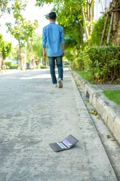Человек, заставляющий бумажник падать на улице
. - Фото, изображение