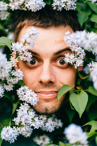 Closeup portrait of young man in beautiful lilac bushes - Valokuva, kuva