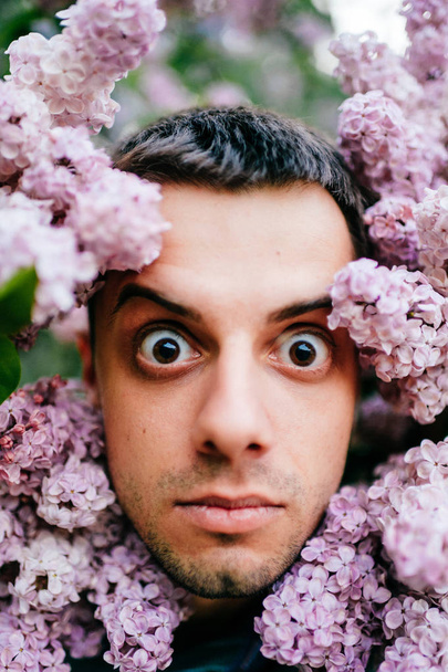 Closeup portrait of young man in beautiful lilac bushes - Foto, Imagen