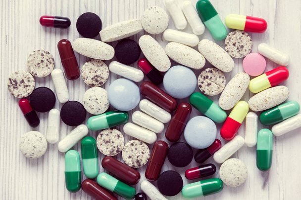 барвисті таблетки на білому дерев'яному фоні
 - Фото, зображення
