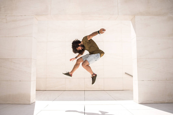 Young sporty man jumping extremely high in limestone building  - 写真・画像