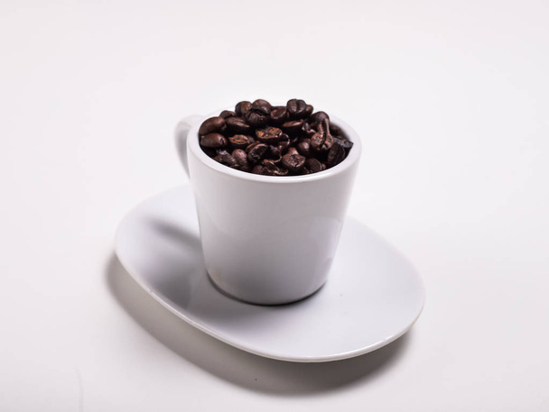 Filiżanka kawy, które są pełne ziarna kawy na białym tle - Zdjęcie, obraz