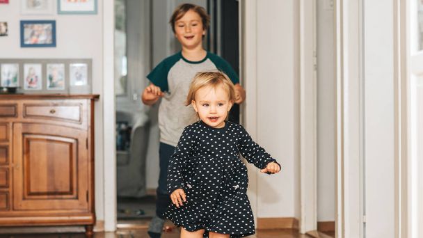 Duas crianças engraçadas brincando juntas em casa, correndo e pulando
 - Foto, Imagem
