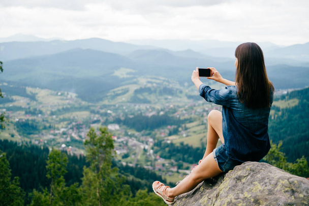 Genç kadın alarak resim Smartphone cep telefonu ile güzel dağları - Fotoğraf, Görsel