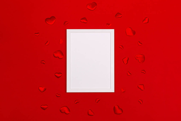 Festive background for Valentines day with blank white photo frame on red with red hearts. - Fotó, kép