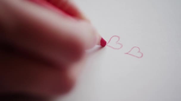 Right hand drawing few red hearts by pencil for sweetheart at Valentine's day. Outlining hearts contours in love message. Hand adumbrating Valentine hearts on handmade card as romantic symbol. Happy Valentine's day. Preparing Valentine gift for adore - Footage, Video