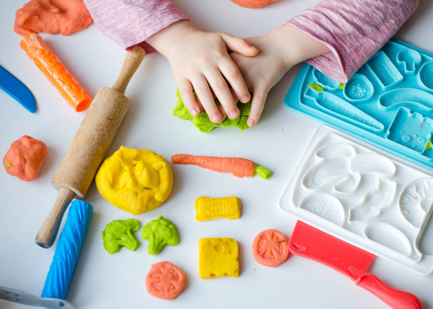 Jeho ruce s barevné hlíny. Dítě hrající a vytvoření vagetables z plastelínou. Dívka, lisování modelování hlíny. Domácí jíl - Fotografie, Obrázek