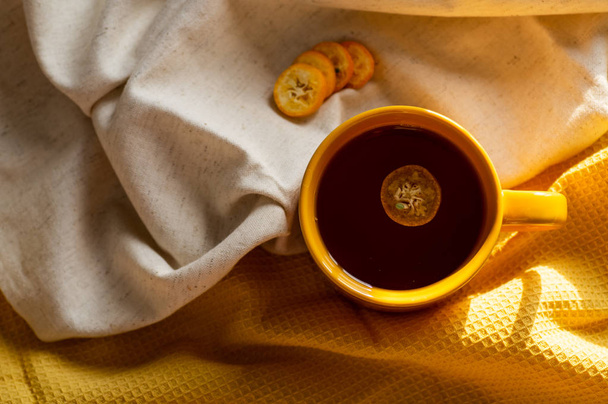 Cup with tea kumquat on yellow background - Photo, Image
