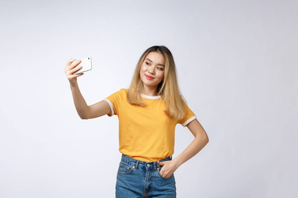 Μεγέθυνση της μικρά Ασίας όμορφη γυναίκα λήψη selfie. Απομονωμένη λευκό φόντο. Ομορφιά και υγιή γυναίκα. - Φωτογραφία, εικόνα