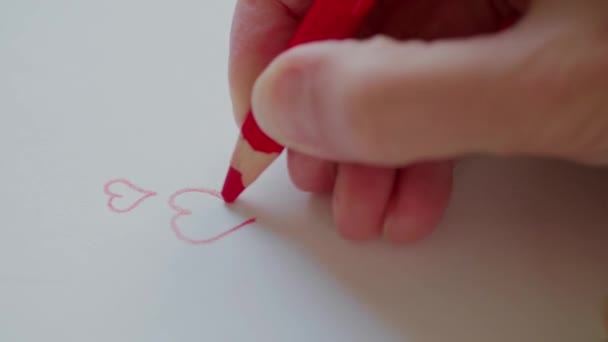 Mano derecha dibujando corazones rojos a lápiz para el amor en el día de San Valentín. Preparación de regalo de San Valentín para la persona adorada. Feliz día de San Valentín. Delineando los contornos de corazones en el mensaje de amor. Corazones de San Valentín adormecidos a mano en tarjeta hecha a mano
 - Metraje, vídeo