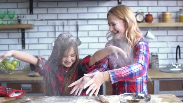 Carefree beautiful young mother and daughter fooling in the kitchen. Mom and child have fun together. - Filmmaterial, Video