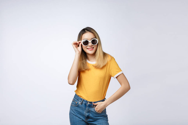 Joven mujer asiática feliz sonriendo en vestido de moda y gafas de sol y sombrero de verano sobre whitebackground con espacio de copia
. - Foto, imagen