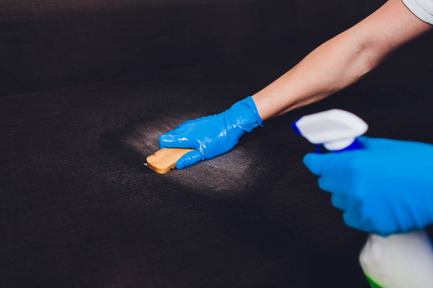 Cropped image. Cleaning concept. Male hand in protective gloves cleaning sofa couch in the room. - Foto, immagini