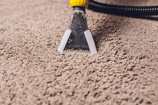 Woman removing dirt from carpet with vacuum cleaner in room. - Fotografie, Obrázek