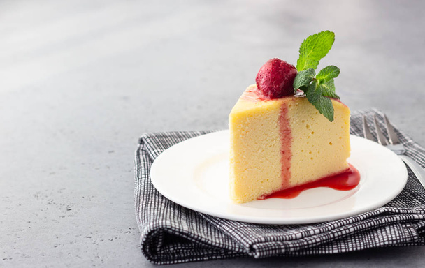 A piece of Japanese cotton cheesecake with mint and strawberry on a white plate. No crust cheesecake. Grey stone or concrete background. Selective focus, copy space.  - Φωτογραφία, εικόνα