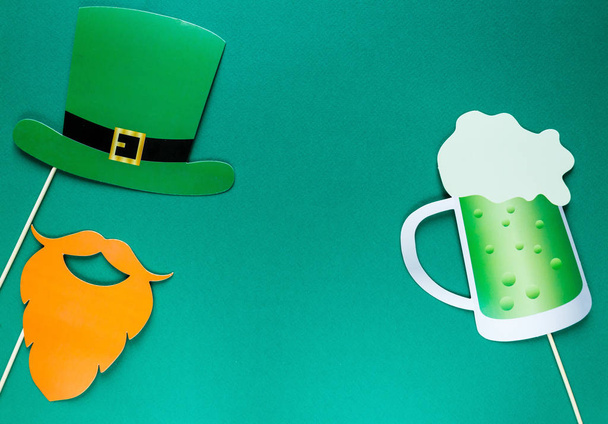 Yaratıcı st Patricks Günü yeşil arka plan. İrlandalı tatil kutlaması fotoğraf stand dekorasyonu ile düz yatıyordu bileşimi: şapka, Gözlük, papyon, dudaklar. Kopya alanı, tebrik kartı, üstten görünüm - Fotoğraf, Görsel